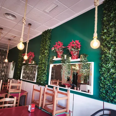 Comedor de Caporale Librilla con pared verde y lámparas de cuerda